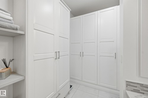 White built-in cabinetry with panel detailing, brushed nickel hardware, open shelving, and tiled flooring - 1961 Adamson Terrace Sw, Edmonton, AB 