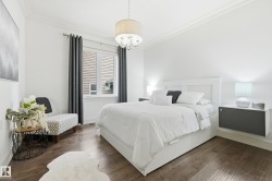 Wood-finish flooring, white walls with crown molding, window with blinds, and a built-in floating nightstand - 