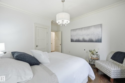 White walls with crown molding, wood-finish flooring, and a contemporary drum chandelier - 1961 Adamson Terrace Sw, Edmonton, AB 