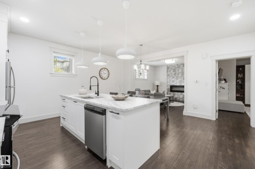White kitchen island with a stone-finish countertop, stainless steel dishwasher, and a black gooseneck faucet - 1961 Adamson Terrace Sw, Edmonton, AB 