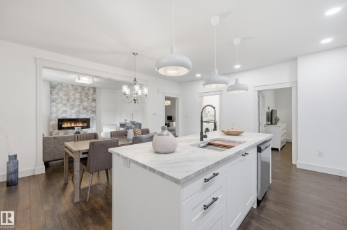 Kitchen island with a built-in sink, white cabinetry, and a light-colored countertop - 1961 Adamson Terrace Sw, Edmonton, AB 