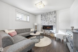 Hardwood-finish flooring with a modern linear fireplace featuring a textured tile surround, and a ceiling-mounted light fixture - 