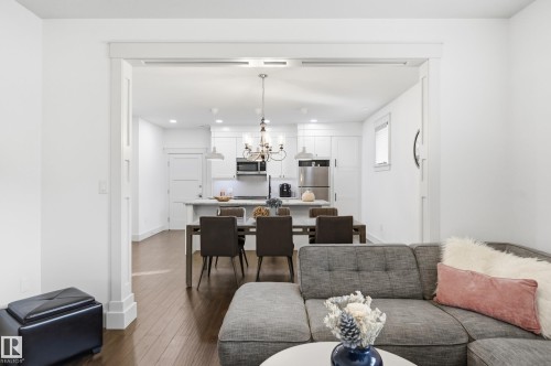 Open living space featuring wood-finish flooring, recessed lighting, and a kitchen island with seating - 1961 Adamson Terrace Sw, Edmonton, AB 