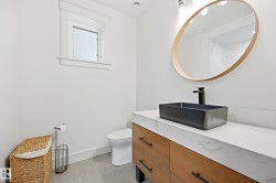 Modern vanity featuring wood-finish cabinetry, a rectangular vessel sink, a stone-finish countertop, and a round wall-mounted mirror - 