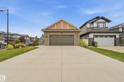 Stone veneer facade with wood-look siding accents, attached double-car garage, concrete driveway, and established landscaping - 