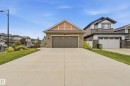 Stone veneer facade with wood-look siding accents, attached double-car garage, concrete driveway, and established landscaping - 1961 Adamson Terrace Sw, Edmonton, AB 
