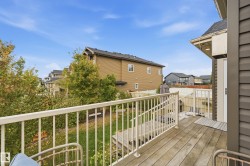 Wood-plank deck with white railing, exterior lighting, and dark gray siding - 