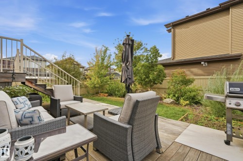 Wood deck with stairs and white railings, stone patio area, and mature landscaping - 1961 Adamson Terrace Sw, Edmonton, AB 