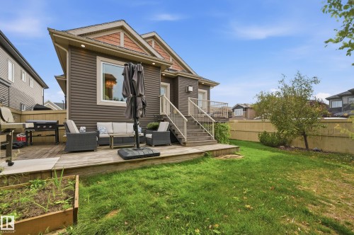 Expansive wooden deck with direct exterior access, leading to a green lawn with a raised garden bed - 1961 Adamson Terrace Sw, Edmonton, AB 
