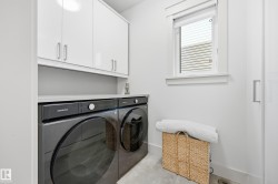 White flat-panel cabinetry with brushed nickel hardware, light-toned countertop, and light gray flooring - 