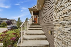 Exterior featuring stacked stone accents, horizontal siding, concrete steps with stone risers, and a prominent front entrance with a wooden door - 