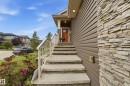 Exterior featuring stacked stone accents, horizontal siding, concrete steps with stone risers, and a prominent front entrance with a wooden door - 1961 Adamson Terrace Sw, Edmonton, AB 
