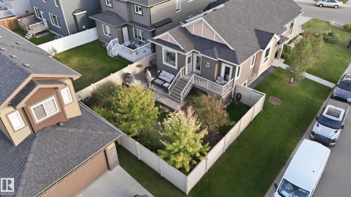 Rear paver patio, fenced yard, mature trees, and exterior stairs with railing - 1961 Adamson Terrace Sw, Edmonton, AB 