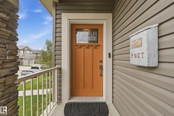 Craftsman-style front door with leaded glass insert, stone veneer column, and horizontal siding - 