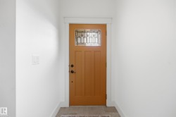 Craftsman-style entry door with decorative glass panels, modern black hardware, and white trim - 