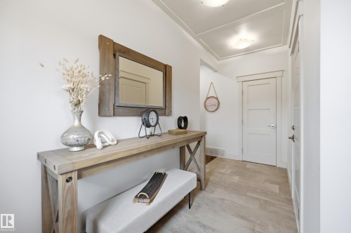 Panel molding ceiling detail, white paneled doors, light wood-finish flooring, and natural wood-tone console table - 1961 Adamson Terrace Sw, Edmonton, AB 