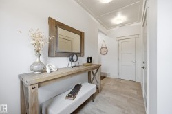 Panel molding ceiling detail, white paneled doors, light wood-finish flooring, and natural wood-tone console table - 