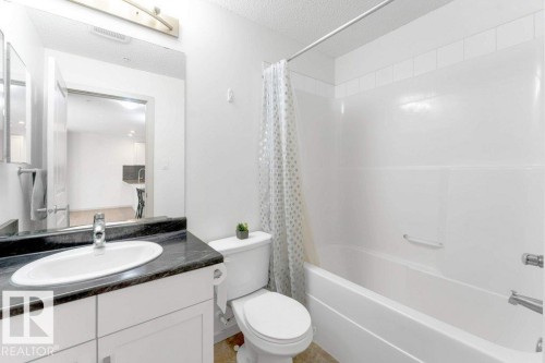 White vanity with a dark countertop and undermount sink - #224 390 Windermere Rd Nw, Edmonton, AB 