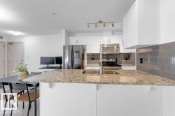 Kitchen featuring light-toned granite countertops, white cabinetry, a subway tile backsplash, and stainless steel appliances - 