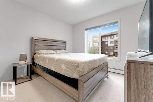 Neutral wall paint, light-toned carpeting, and a large window providing natural light - #224 390 Windermere Rd Nw, Edmonton, AB 
