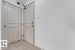 Light wood-finish flooring with white paneled doors and modern door hardware - 