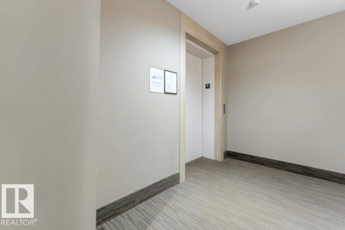 Elevator access with light wood-finish door frame, light wood-finish flooring, and light neutral wall paint - #224 390 Windermere Rd Nw, Edmonton, AB 