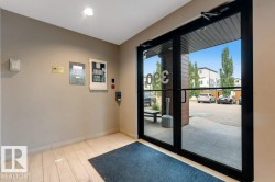 Double glass entry doors with black framing, wood-finish flooring, and light-toned wall paneling - 