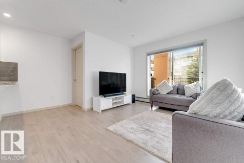 Light wood-finish flooring with crisp white walls - #224 390 Windermere Rd Nw, Edmonton, AB 