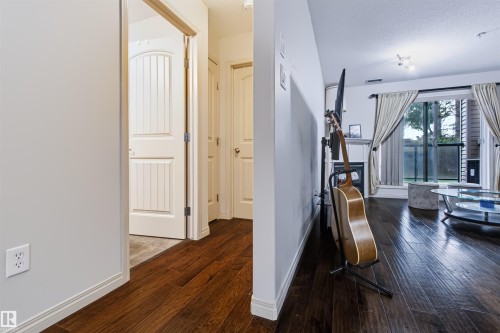 Dark wood-finish flooring throughout, white baseboards, and a sliding glass door leading to an outdoor space - #155 2096 Blackmud Creek Dr Sw, Edmonton, AB 