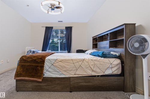 Carpeted flooring, window with dark drapes, and a ceiling fan with integrated lighting - #155 2096 Blackmud Creek Dr Sw, Edmonton, AB 