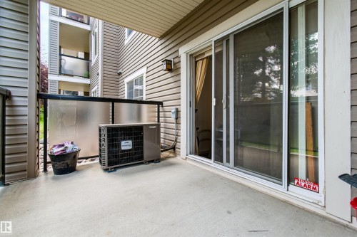Concrete patio with sliding glass doors, aluminum railing, and an exterior wall light - #155 2096 Blackmud Creek Dr Sw, Edmonton, AB 