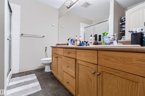 Dual vanity with wood-finish cabinetry, integrated sinks, and polished chrome fixtures - #155 2096 Blackmud Creek Dr Sw, Edmonton, AB 