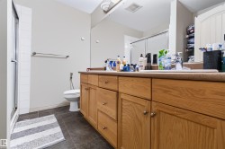 Dual vanity with wood-finish cabinetry, integrated sinks, and polished chrome fixtures - 