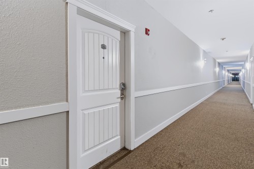 White entry door with decorative vertical paneling and arch detail - #155 2096 Blackmud Creek Dr Sw, Edmonton, AB 
