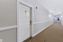 White entry door with decorative vertical paneling and arch detail - #155 2096 Blackmud Creek Dr Sw, Edmonton, AB 