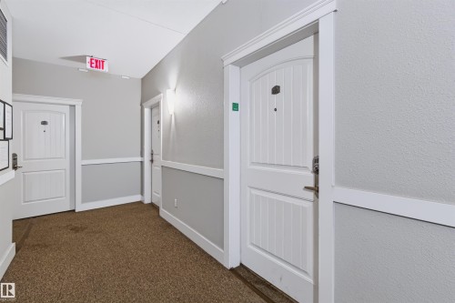 Hallway with textured walls, wall sconces, white paneled doors, and carpet flooring - #155 2096 Blackmud Creek Dr Sw, Edmonton, AB 