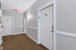 Hallway with textured walls, wall sconces, white paneled doors, and carpet flooring - 