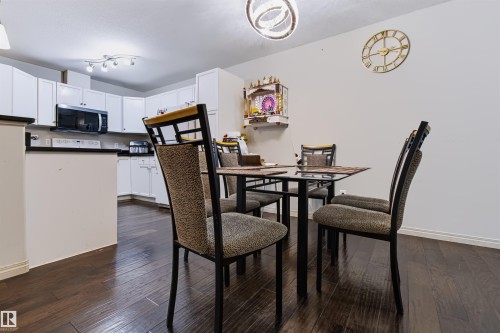White cabinetry with dark countertops, built-in microwave, and wood-finish flooring - #155 2096 Blackmud Creek Dr Sw, Edmonton, AB 