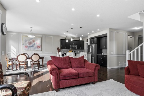 Open-concept living area with dark wood-finish flooring, recessed lighting, and decorative wall molding - 8515 19 Avenue Sw, Edmonton, AB 