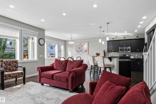 Open-concept living space with dark wood-finish flooring, recessed lighting, and ample natural light through multiple windows - 8515 19 Avenue Sw, Edmonton, AB 