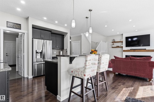 Open-concept kitchen with dark wood-finish flooring, stainless steel appliances, and a kitchen island with pendant lighting - 8515 19 Avenue Sw, Edmonton, AB 