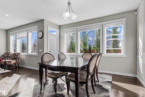 Spacious dining area featuring wood-finish flooring, multiple large windows, and a built-in decorative wall panel - 8515 19 Avenue Sw, Edmonton, AB 