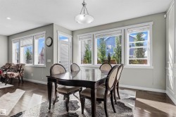 Spacious dining area featuring wood-finish flooring, multiple large windows, and a built-in decorative wall panel - 