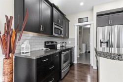 Kitchen featuring dark wood-finish cabinetry, stainless steel appliances, granite countertops, and subway tile backsplash - 