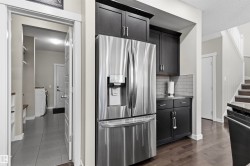 Stainless steel French door refrigerator, dark wood-finish cabinetry, subway tile backsplash, dark granite-style countertop, and dark wood-finish flooring - 
