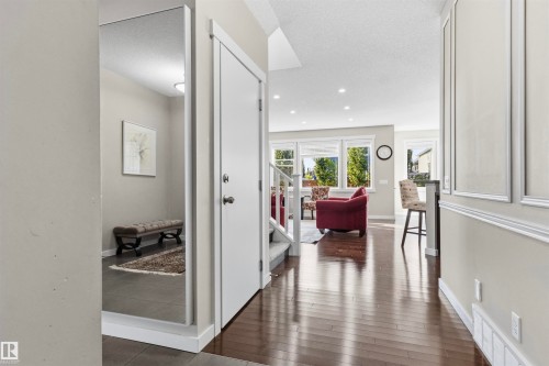 Rich wood-finish flooring extending through living areas, white painted walls with decorative paneling, recessed lighting, and large windows - 8515 19 Avenue Sw, Edmonton, AB 
