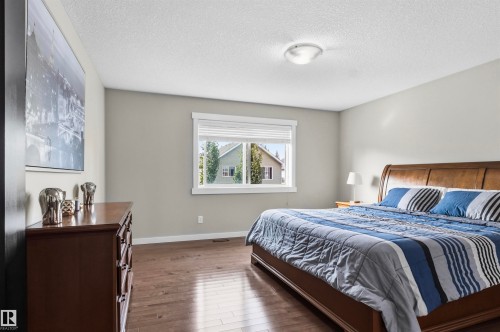 Hardwood-finish flooring, neutral wall tones, window with white trim, and a ceiling-mounted light fixture - 8515 19 Avenue Sw, Edmonton, AB 