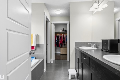 Dual vanity with undermount sinks, chrome fixtures, and a dark countertop - 8515 19 Avenue Sw, Edmonton, AB 