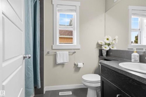 Vanity with an integrated sink, dark wood-finish cabinetry, and a dark countertop - 8515 19 Avenue Sw, Edmonton, AB 