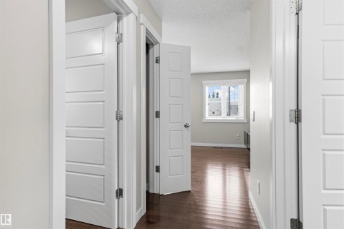 Wood-finish flooring throughout, white paneled doors, and a window with blinds - 8515 19 Avenue Sw, Edmonton, AB 